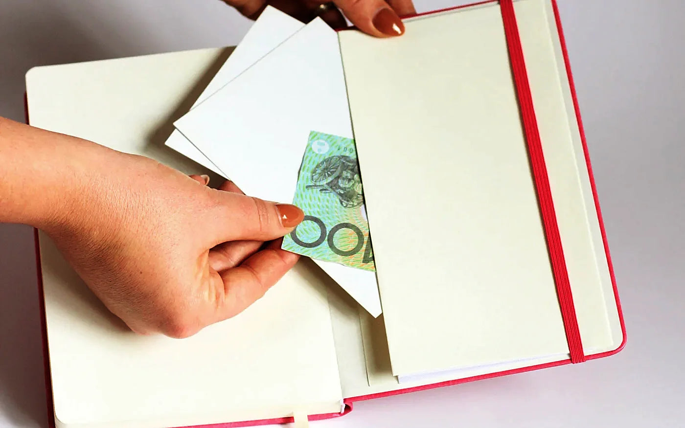 Una mano guardando billetes en el bolsillo interior de la Planner 2027